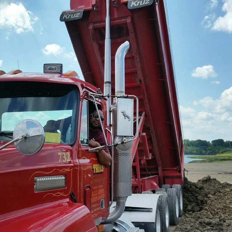 Red Trim's Trucking dump truck operating with raised bed